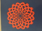 an intricate orange paper craft decoration created by Allan Troxler ’69 